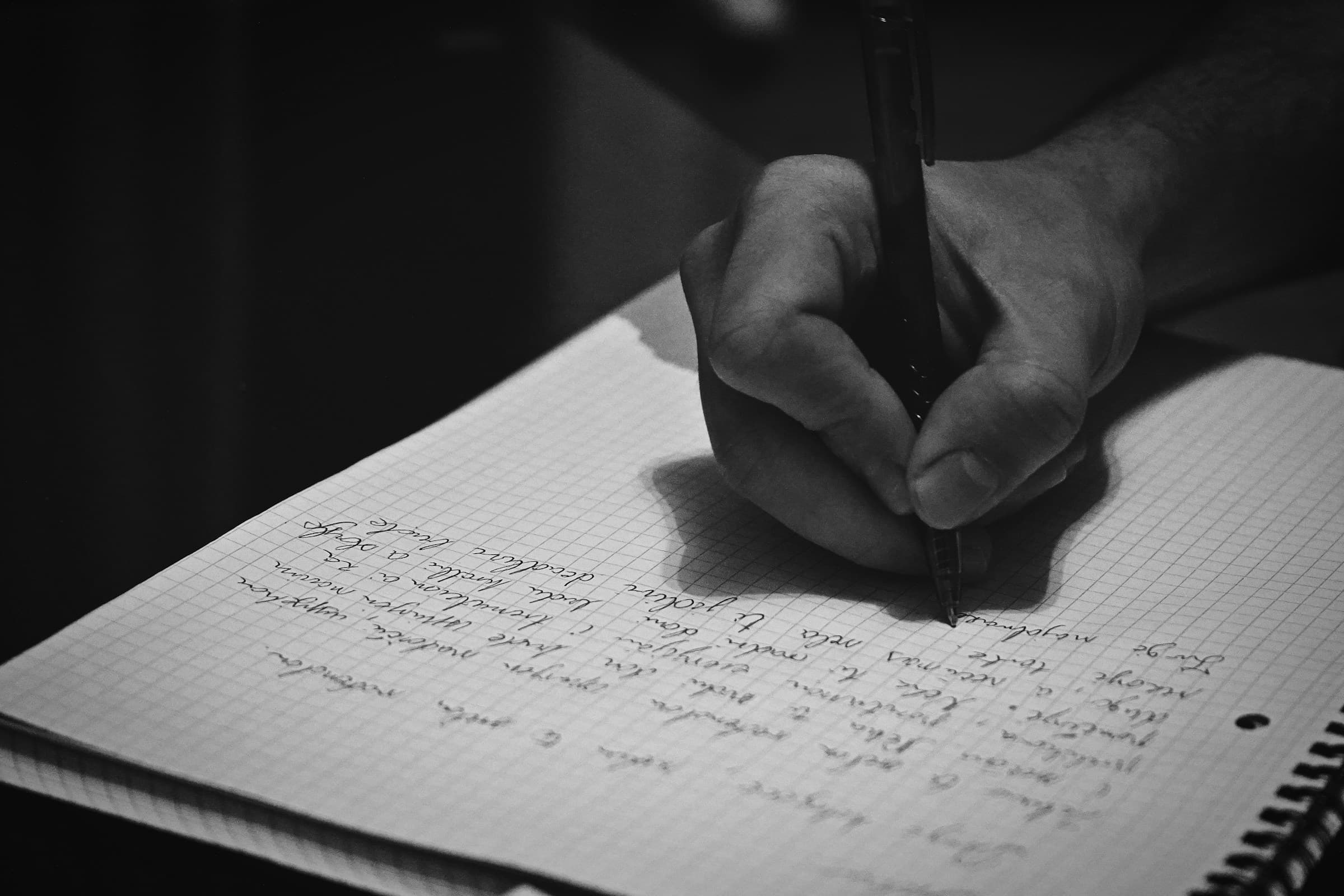 A hand writing in a notebook — careful documentation, real focus